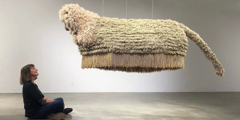 Artist Phyllis Green sits looking up at her piece